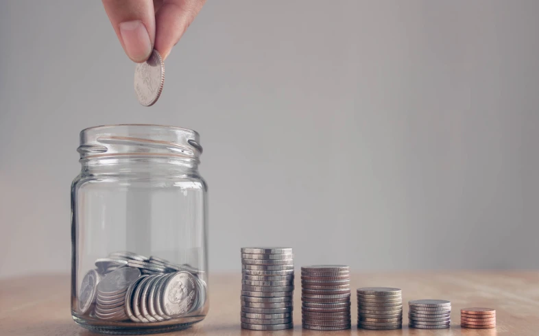 Hand placing coin into savings jar