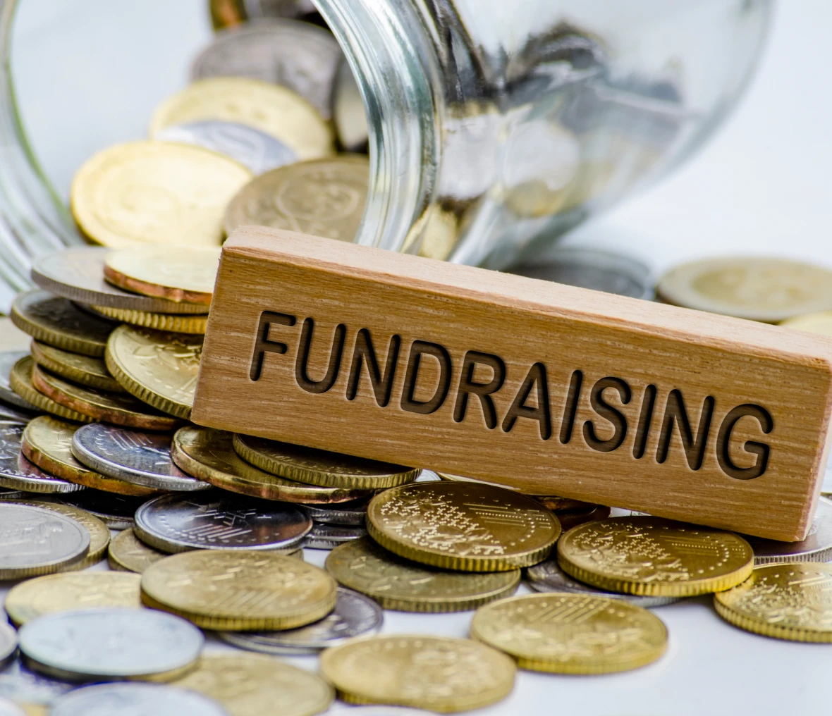 Coins spilling from jar, fundraising concept