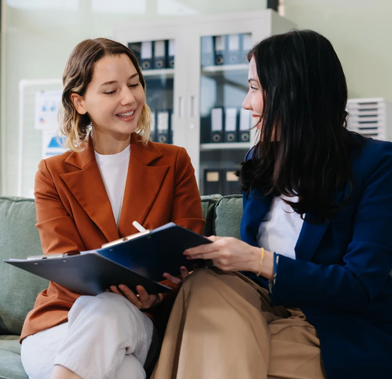 Women discussing documents on a couch
